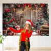A woman in a red sweater points toward a Christmas woodland backdrop featuring a decorated tree, gifts, and snow.