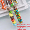 A collection of mini glass bottles with cork stoppers filled with colorful beads and candies for DIY crafts