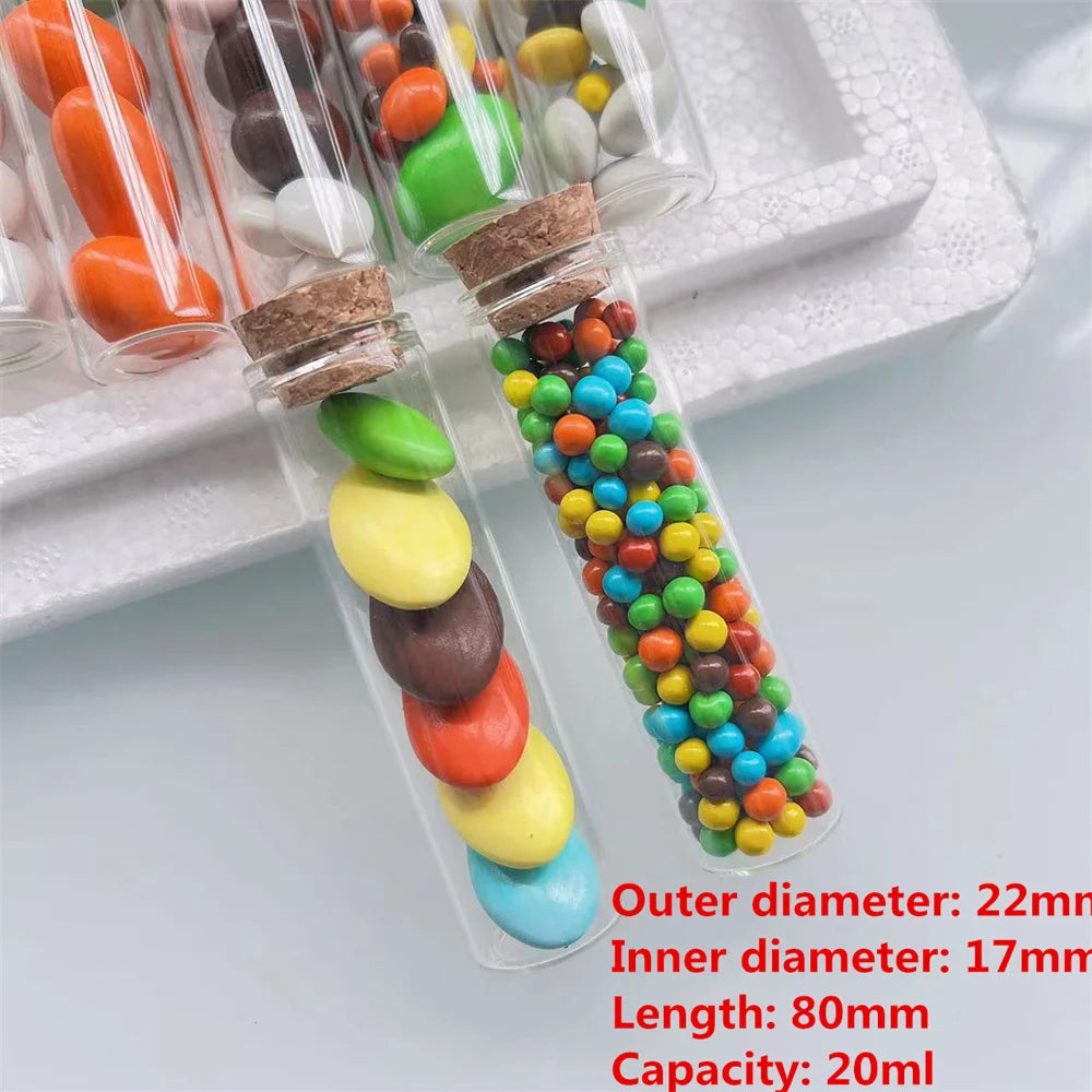 A collection of mini glass bottles with cork stoppers filled with colorful beads and candies for DIY crafts
