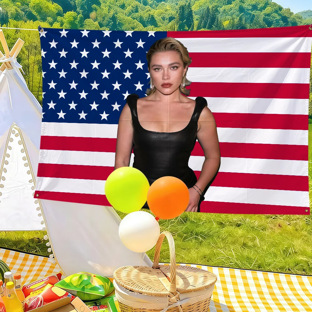 A woman in a black top stands in front of an American flag banner with yellow and orange balloons on a checkered blanket.
