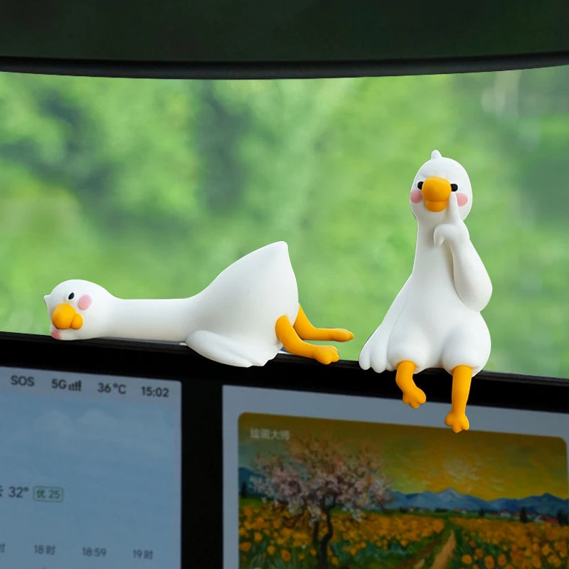 Figurine de canard en résine blanche avec des pattes jaunes, présentée dans un cadre vitré.