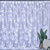 White sheer curtain illuminated by numerous twinkling fairy lights