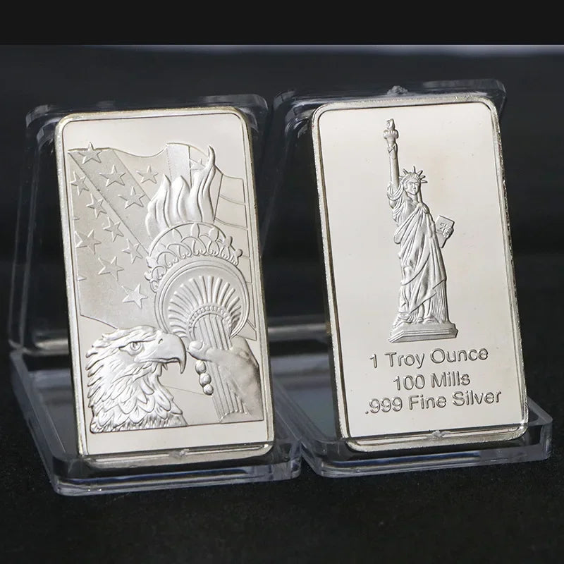 A silver bullion bar replica featuring a depiction of a figure holding a staff and an eagle, set in protective plastic packag