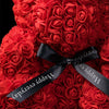 Un bouquet de roses rouges attaché avec un ruban noir, utilisé comme décoration de ours en rose.