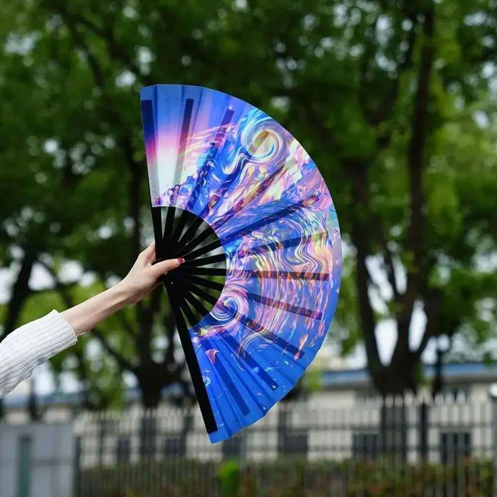 A hand holds an open UV fluorescent folding fan displaying vibrant iridescent colors and swirling patterns.