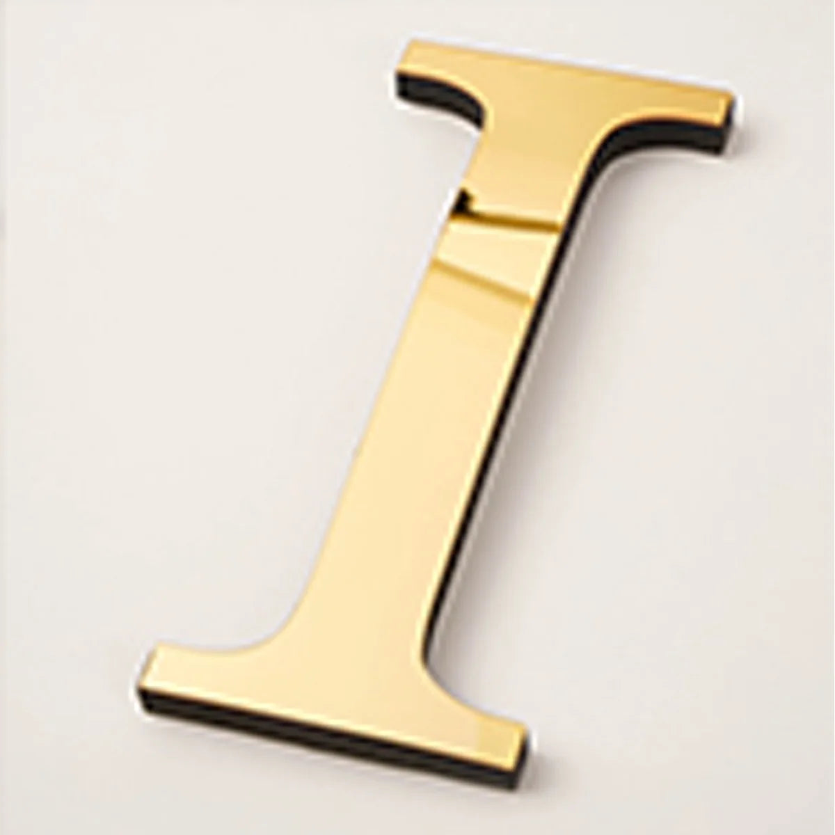 A gold acrylic mirror letter T wall sticker, 20cm in size.