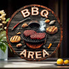 Panneau en bois rond décoré d'initiales BBQ et du mot AREA, avec divers outils de grillade et viandes.