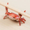 A small, crab-shaped desk organizer made of resin, featuring a pen and phone holder, resting on a wooden surface.
