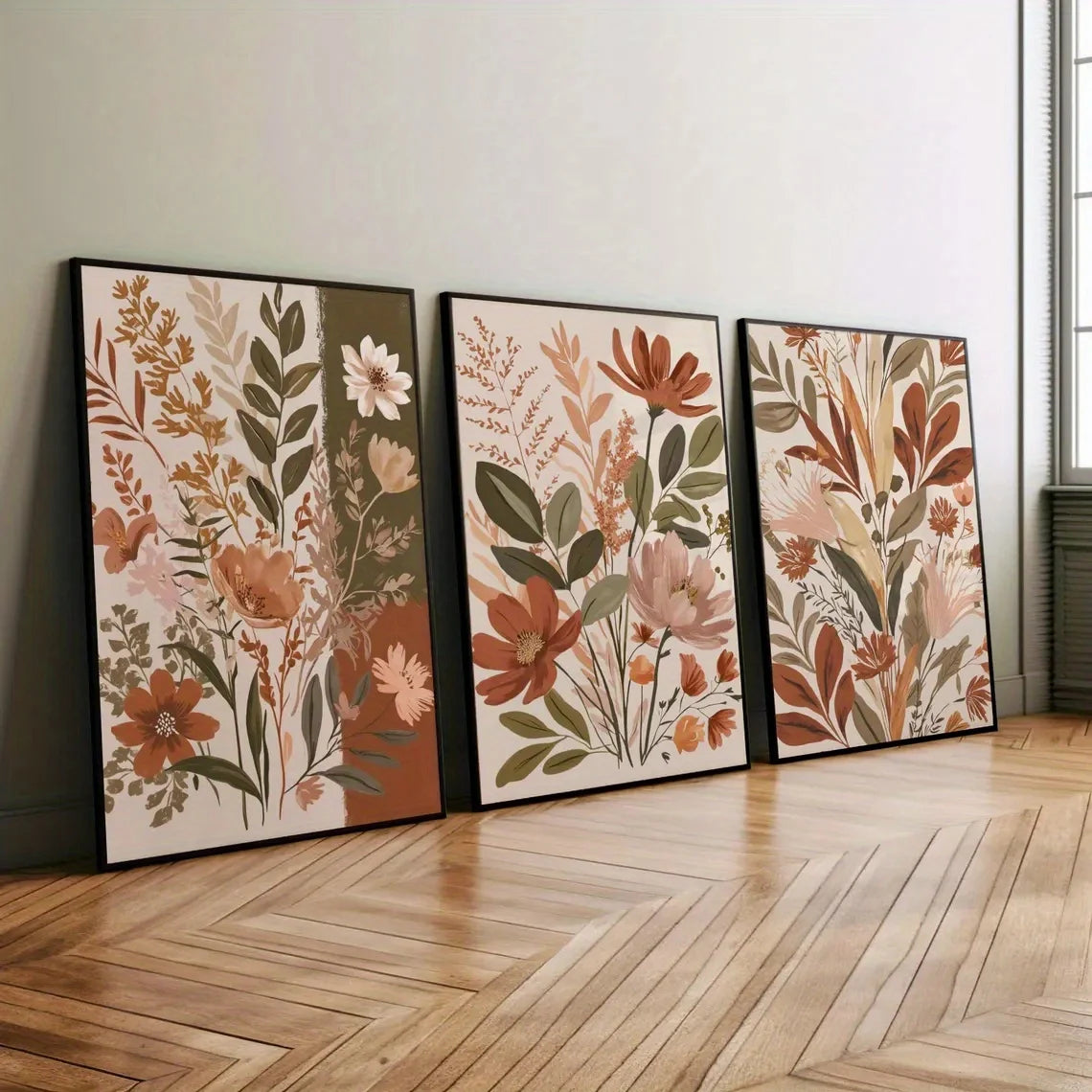 A set of three framed canvas art prints featuring soft floral and botanical designs in muted earth tones on a light wall.