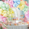 A display of pastel rainbow latex balloons and cupcakes for a party decoration setup.