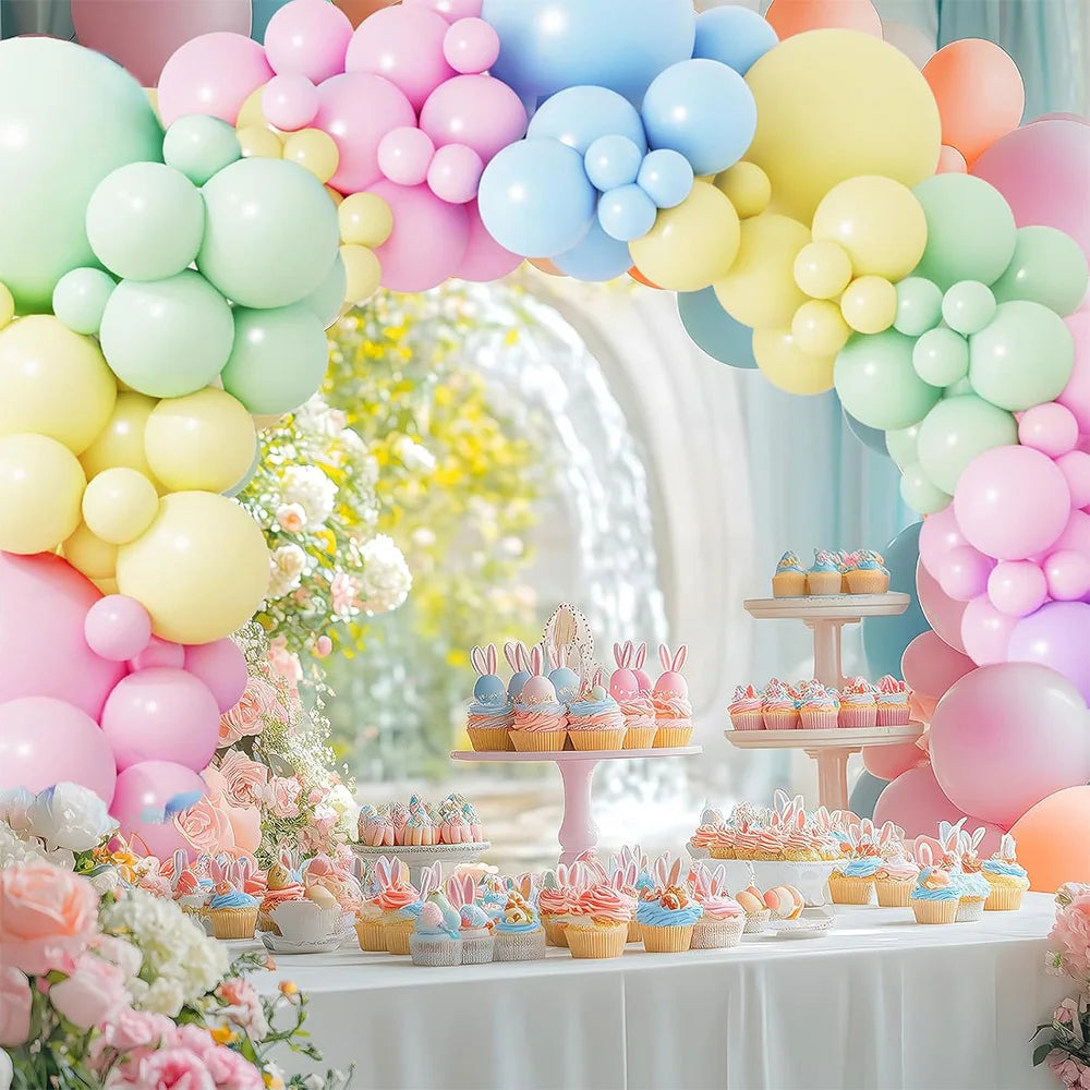 A display of pastel rainbow latex balloons and cupcakes for a party decoration setup.