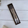 A package of elegant spiral birthday candles in a dark box with a clear insert on a white wooden surface.
