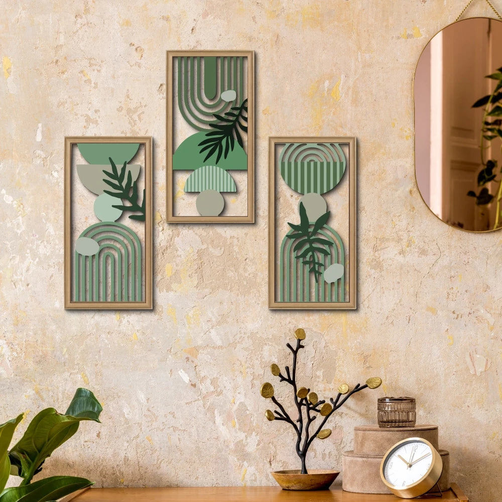Three framed botanical wall art pieces featuring green and muted tones displayed on a textured beige wall.