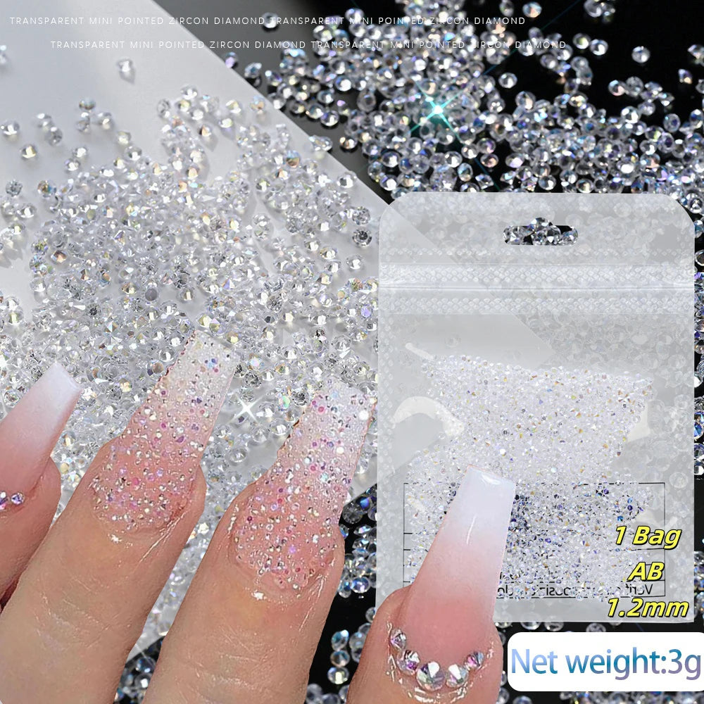 Close-up of fingers applying iridescent nail rhinestones onto a clear nail, with loose stones and packaging visible.