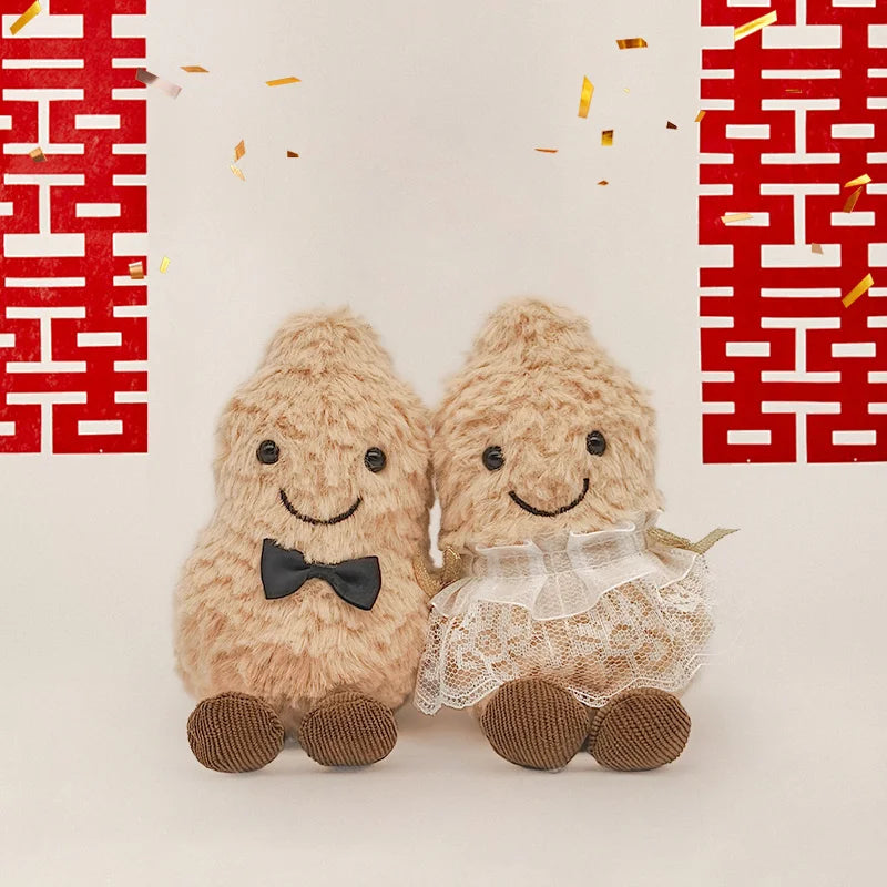 Two fluffy beige plush toys resembling peanuts with black bowties and reindeer antlers against a red geometric background