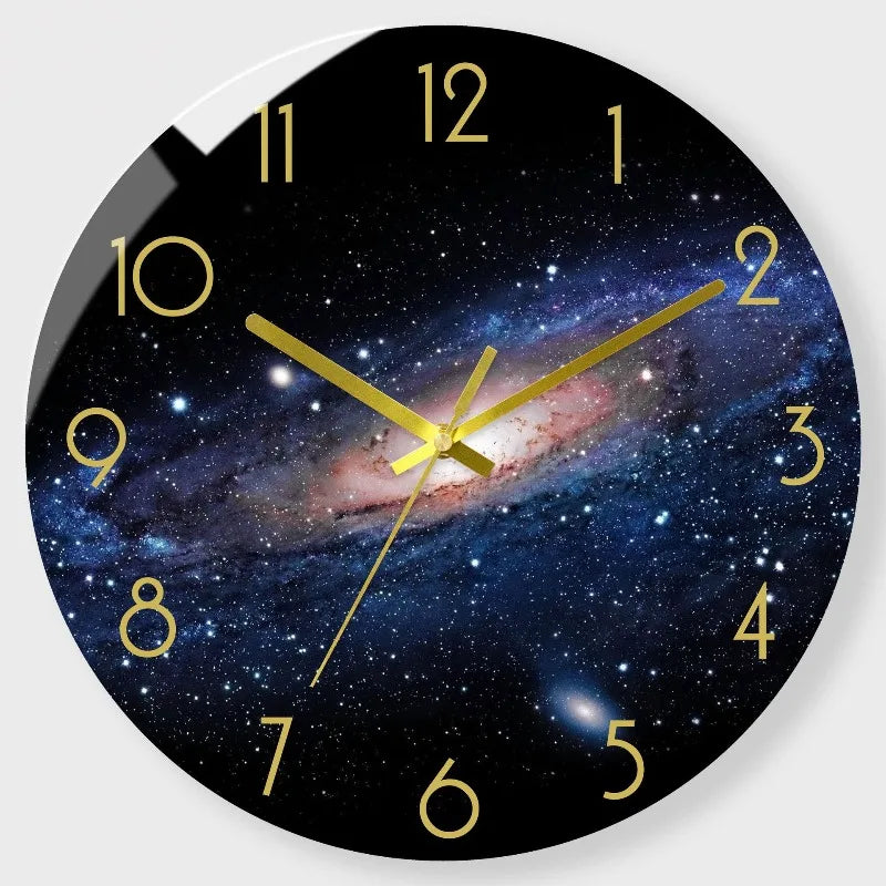 A round wall clock face with a dark blue and purple galaxy design and gold hour markers.