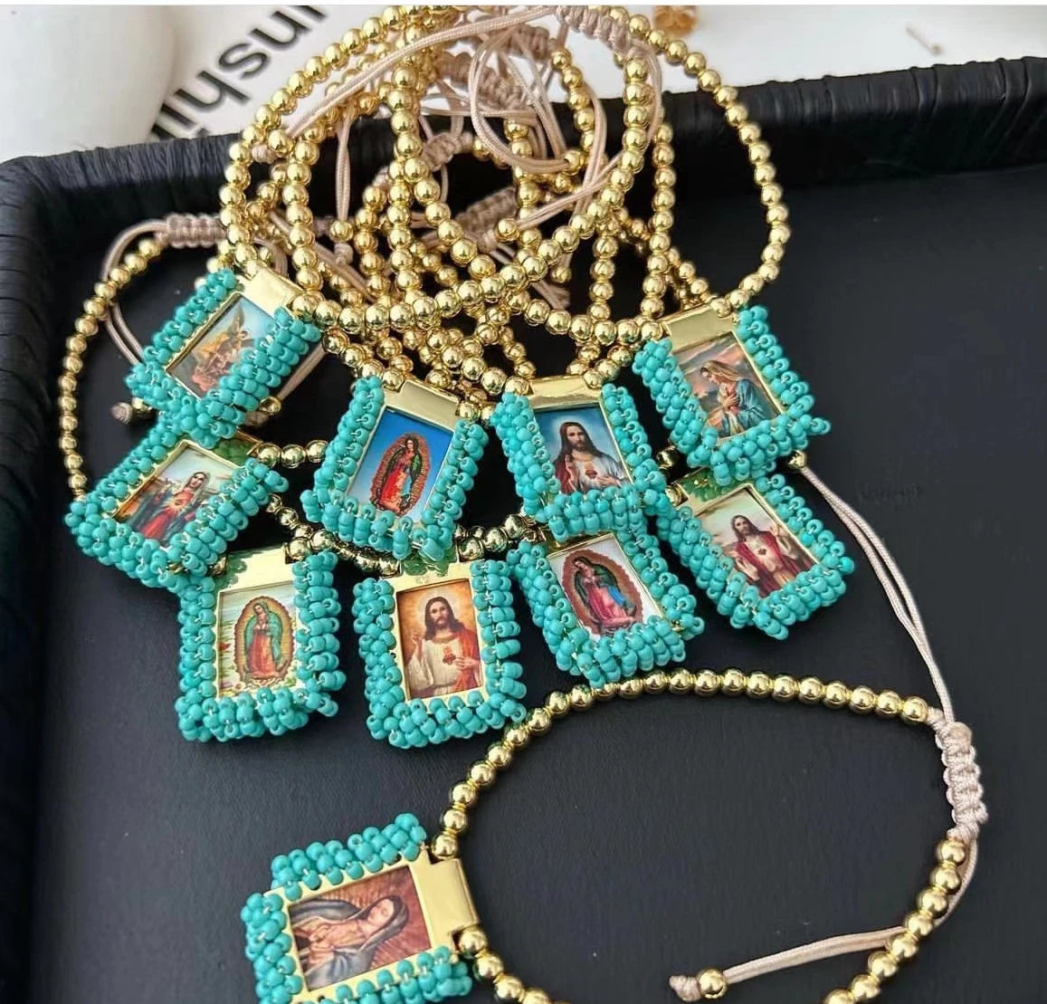 Gold-plated charm bracelet featuring turquoise beads and small framed images of the Virgin Mary Guadalupe.