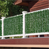 White fence panels covered with artificial green ivy hedge foliage installed on a wooden deck railing.