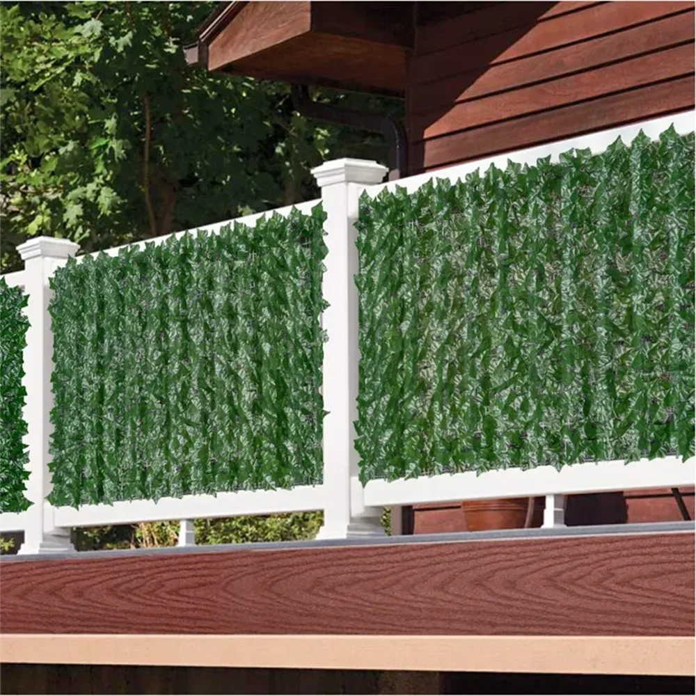 White fence panels covered with artificial green ivy hedge foliage installed on a wooden deck railing.