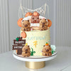 A tiered cake decorated with capybara animal figures and a banner, suitable for a birthday party.