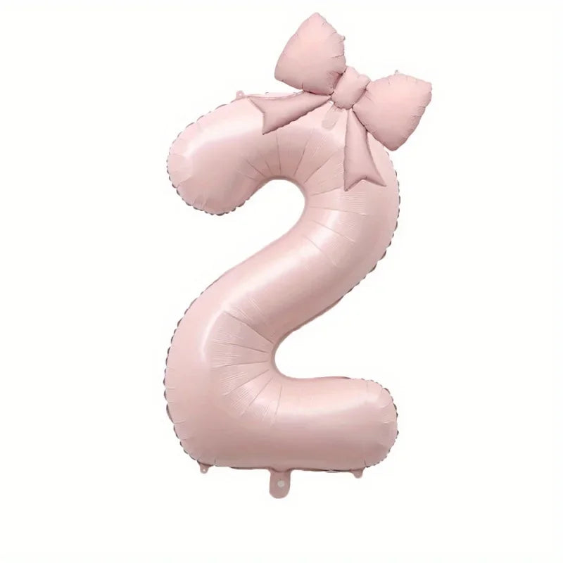 A large pink foil number balloon shaped like the number 2 with a bow.