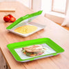 A bright green stackable reusable food preservation tray holding a portion of yellow food on a wooden table.