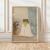 A framed canvas print featuring a green frog sitting on a white cloth against a muted background.