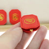 A hand holds a small red Fengshui lucky turtle charm with gold detailing against a light background.