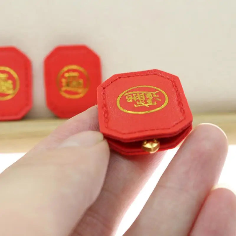 A hand holds a small red Fengshui lucky turtle charm with gold detailing against a light background.