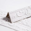 White self-adhesive PVC corner trim with a 3D textured edge shown in a close-up view.