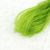 A bundle of bright green decorative fishtail yarn ribbon laid on a white surface.