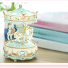 Handmade resin carousel music box with a light blue and cream painted carousel figure on a wooden surface.