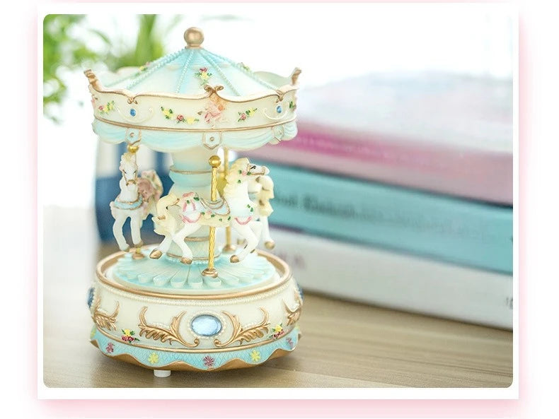 Handmade resin carousel music box with a light blue and cream painted carousel figure on a wooden surface.
