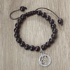 A black beaded bracelet with a silver zodiac charm is displayed on a neutral background.