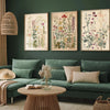 Three canvas prints featuring retro wildflower landscapes displayed on a dark green wall above a sofa.