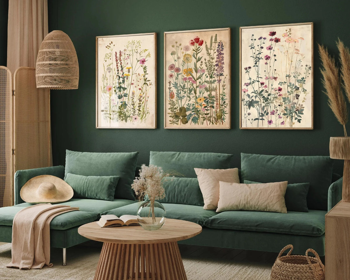 Three canvas prints featuring retro wildflower landscapes displayed on a dark green wall above a sofa.