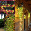 Green leaf string lights draped over a wooden door and railing, creating an ivy vine decoration.