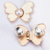 A gold-toned butterfly button featuring a pearl in the center, used for tightening jeans.