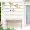 Three vintage wooden bird wall decorations painted in yellow and blue on a white siding.