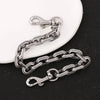 A silver and black two-tone metal chain necklace with a clasp and pendant resting on a white surface.
