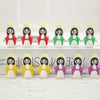 A row of mini Virgin Mary resin statues in various colors including white, red, green, and yellow.