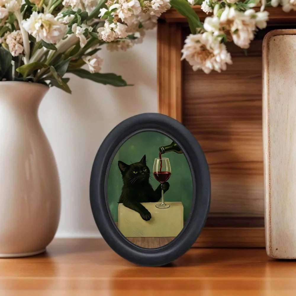 Wall art featuring a black cat drinking wine in a glass, set against a dark green background.
