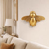 Handgefertigte goldene Bienenwandskulptur an einer cremefarbenen Wand.