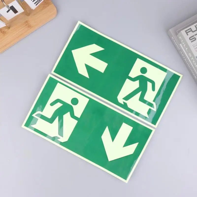 A green photoluminescent emergency exit sign decal showing directional arrows and a silhouette of a person walking.