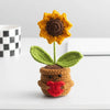 Handmade crochet sunflower desk companion with a smiling face, featuring orange petals and green leaves.