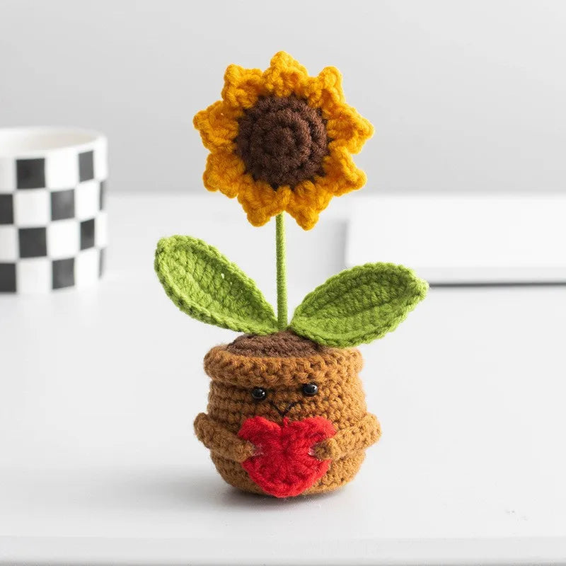 Handmade crochet sunflower desk companion with a smiling face, featuring orange petals and green leaves.