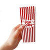 A hand holds a vertical stack of red and white striped paper snack boxes.