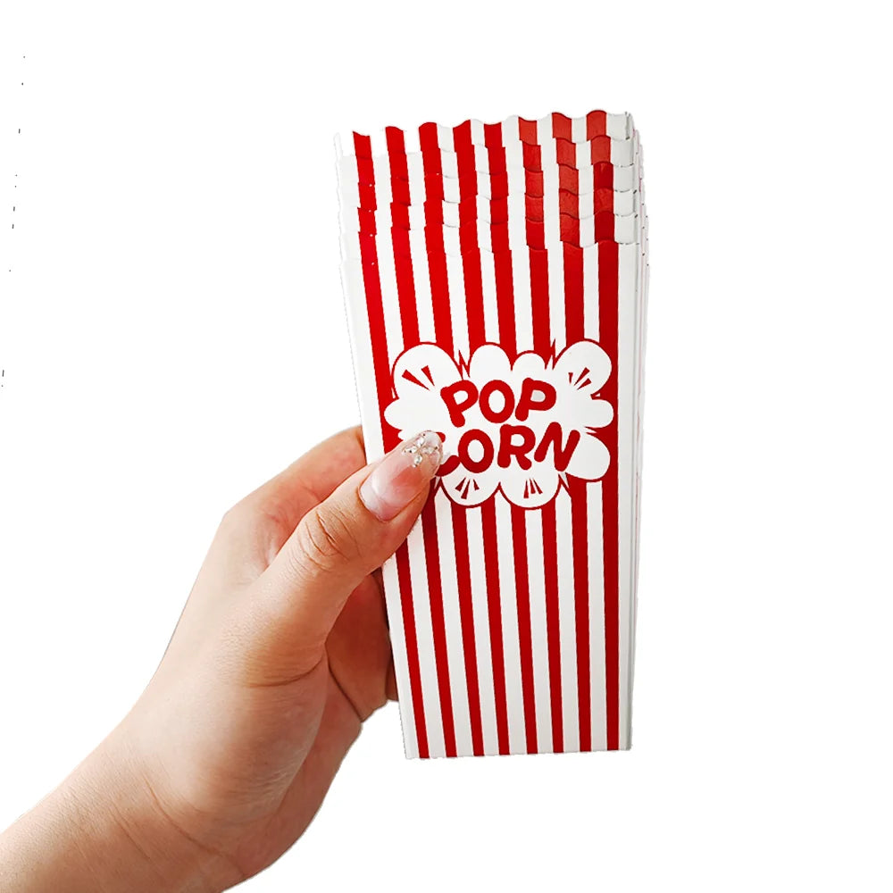 A hand holds a vertical stack of red and white striped paper snack boxes.