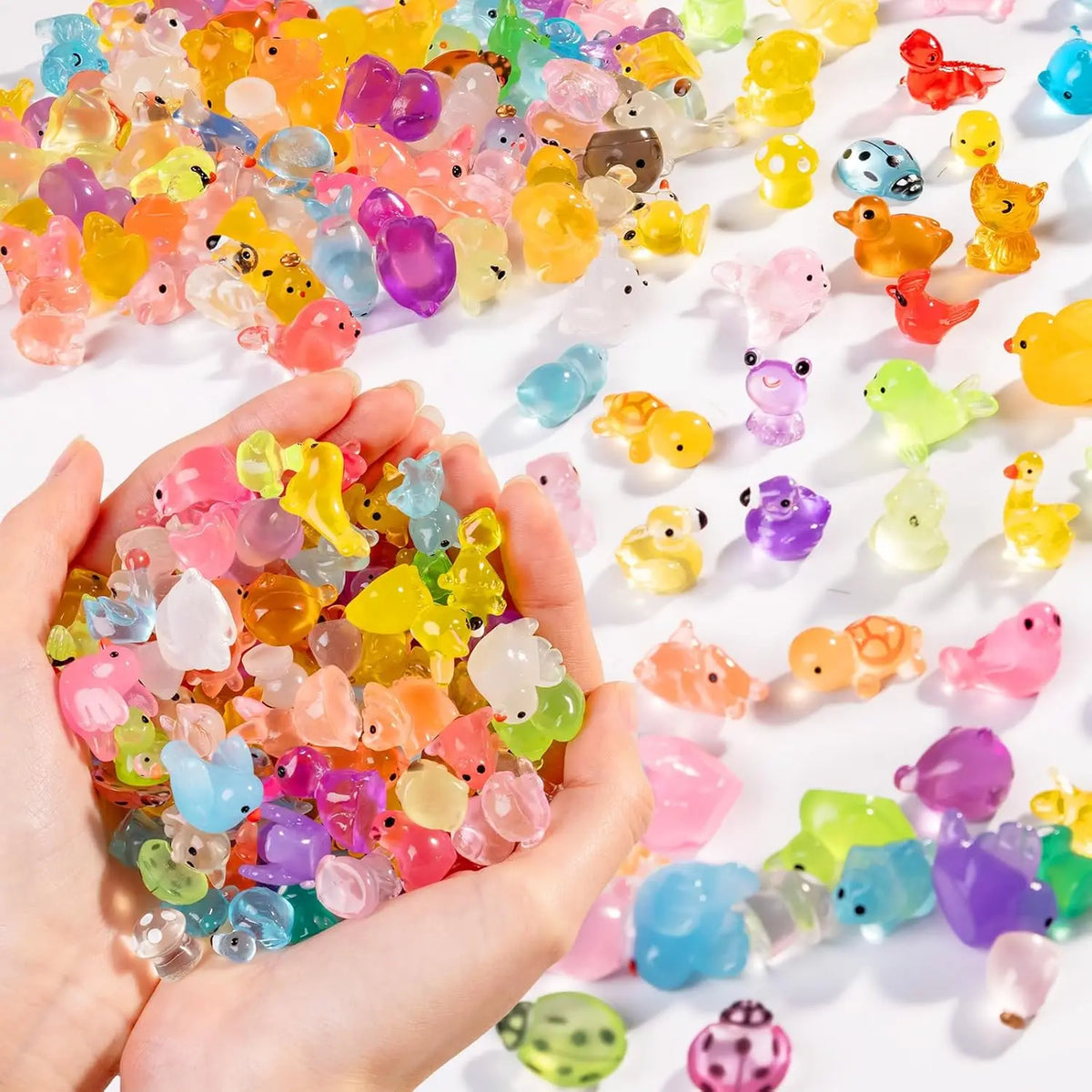 A hand holds a collection of colorful glowing resin animal figurines for desk and garden décor.
