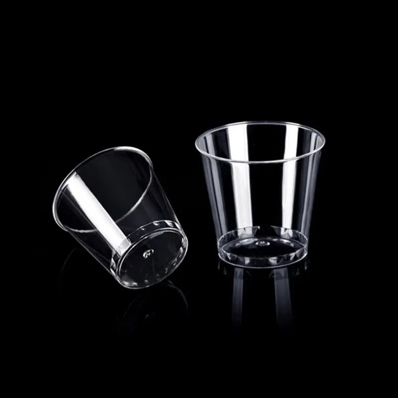 A clear glass shot glass is shown against a black background.